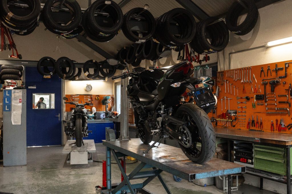 atelier-de-pmh-motos-avec-motos-sur-plateformes-pneus-suspendus-et-panneau-d-outils-en-fond